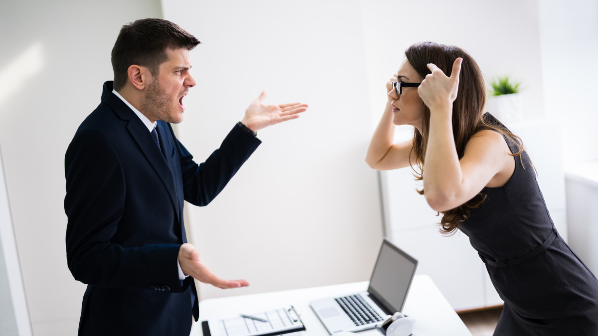 Side View Of Business People Quarreling At Desk In Office