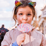Little girl with big lollipop is playing and having fun in the park