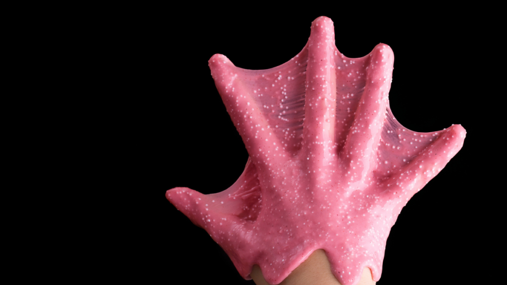 The hand of the child is covered with glue and glitter