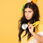 Upset girl with trash in hair holding bag with rubbish isolated on yellow.