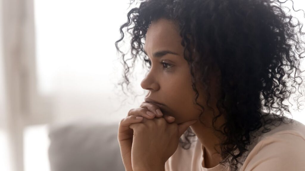 Close up side profile view of pensive young african American woman thinking of relationships problems.