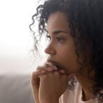 Close up side profile view of pensive young african American woman thinking of relationships problems.