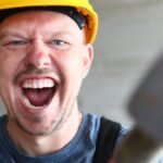Portrait of screaming male holding big sturdy construction tool.