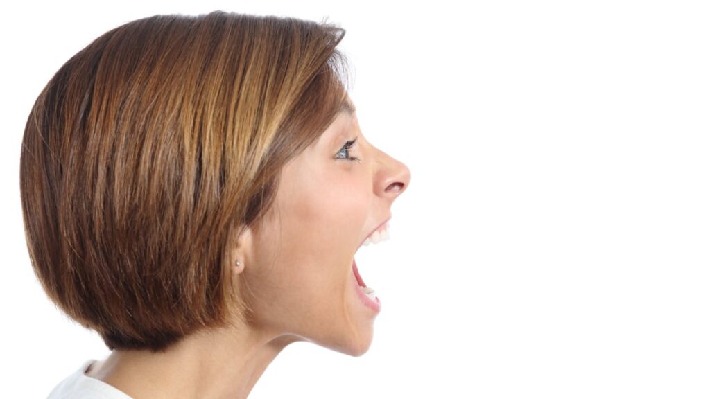 Profile of an angry young woman shouting isolated on a white background.