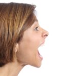 Profile of an angry young woman shouting isolated on a white background.