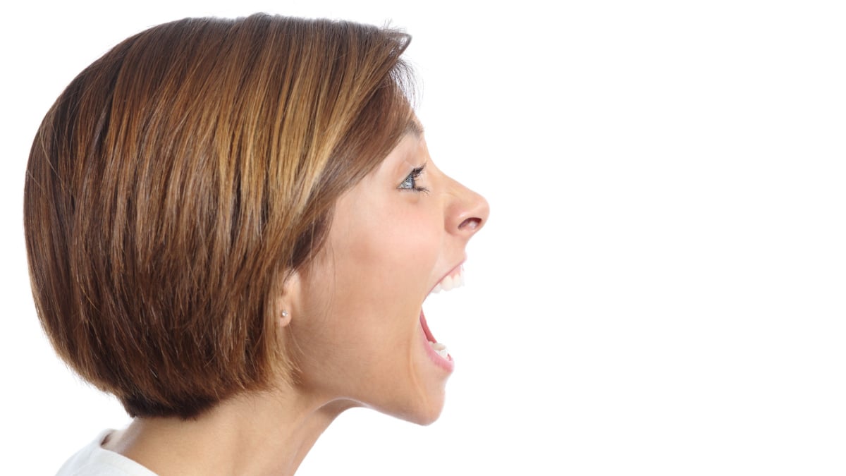 Profile of an angry young woman shouting isolated on a white background.