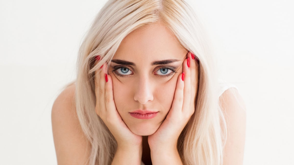 Blonde face is laying on her hands. The concept of frustration,fatigue, sadness. studio photo on white background.