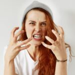 Close up isolated portrait of young annoyed angry woman holding hands in furious gesture.