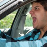 An irritated young man driving a vehicle is expressing his road rage..