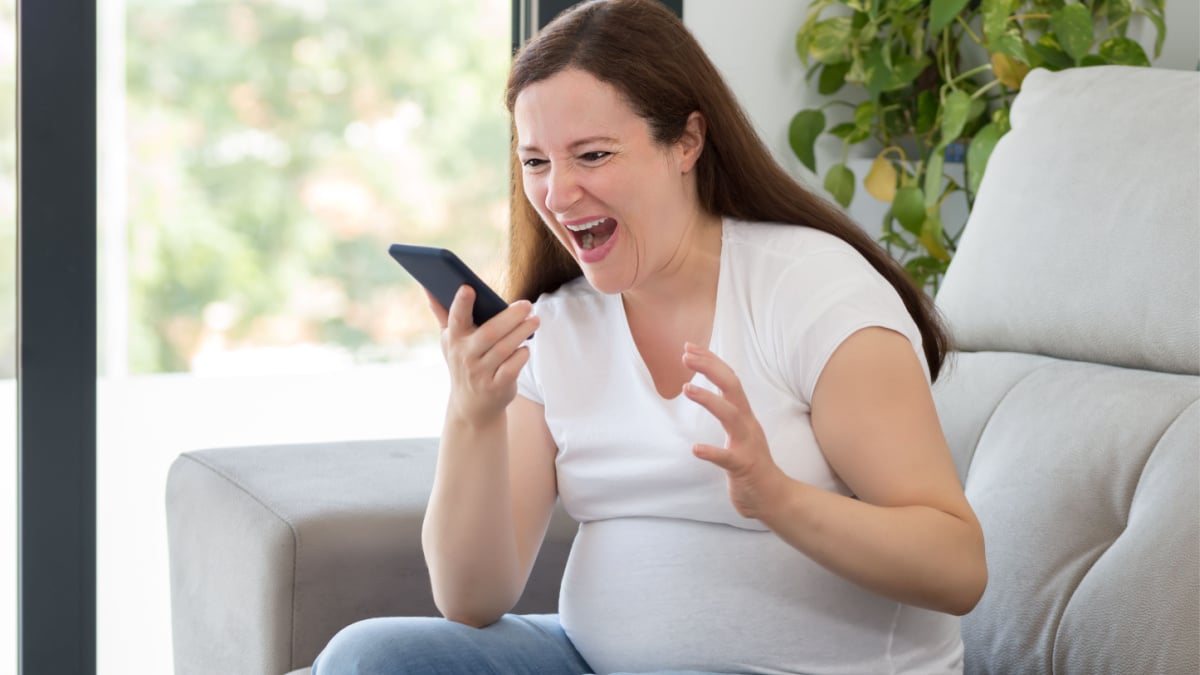 Shot of a furious pregnant woman shouting to smart phone at home.