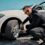 a man in a suit changes the wheel of a car.