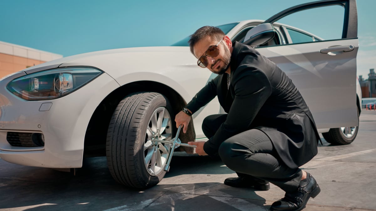 a man in a suit changes the wheel of a car.