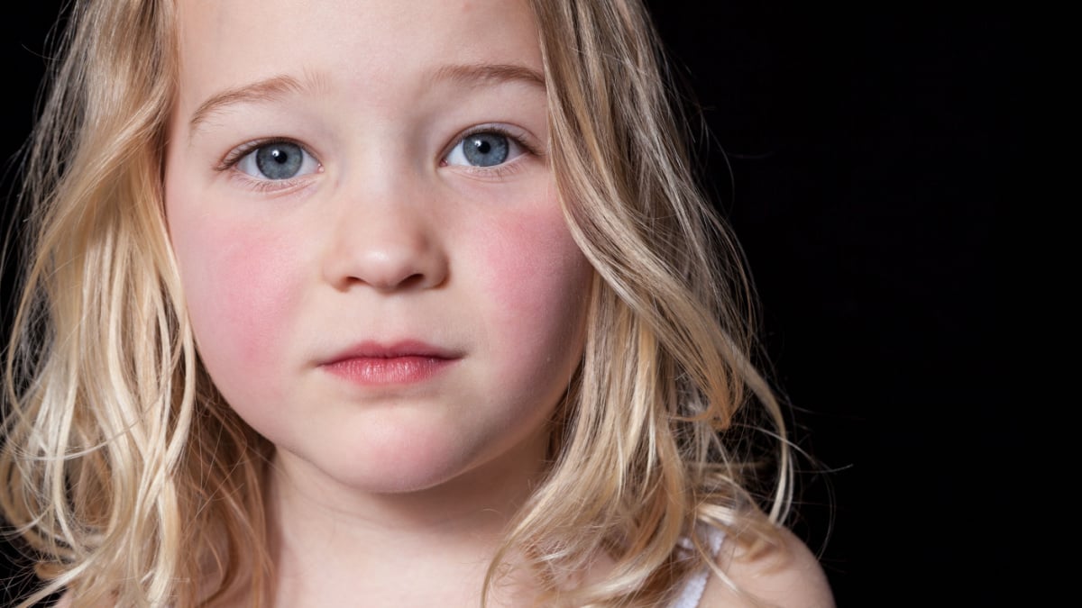 Close up portrait of a young girl on black background.