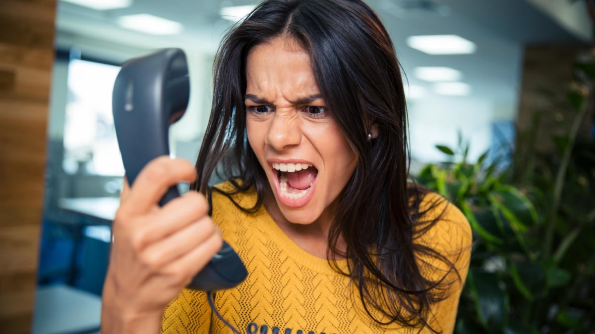 Angry businesswoman shouting on phone in office.