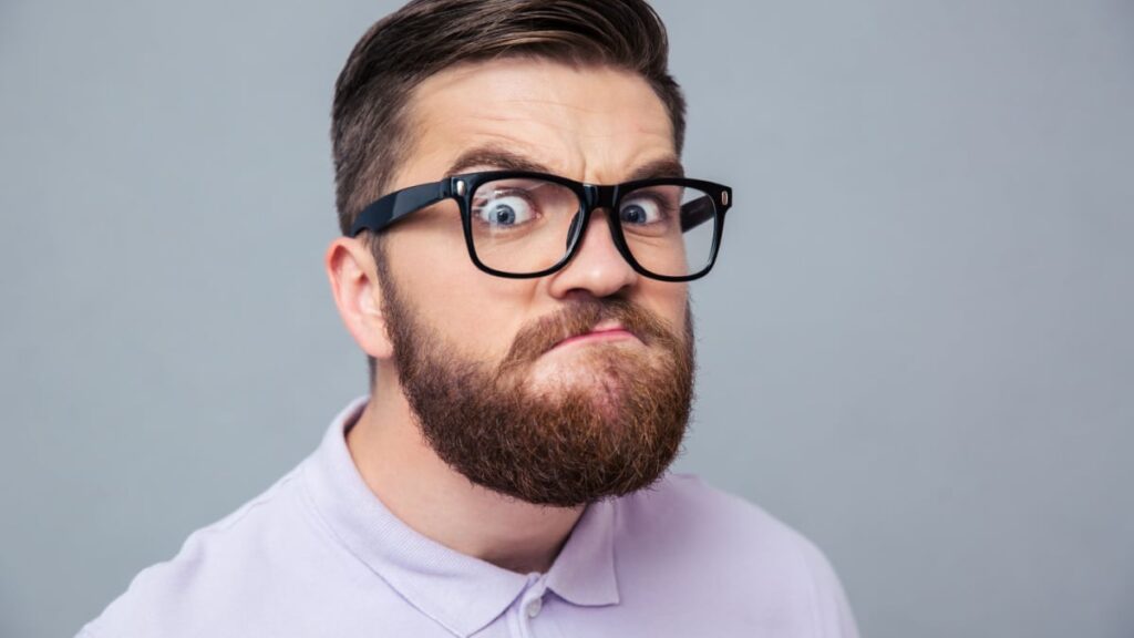 Portrait of a funny hipster man looking at camera over gray background.