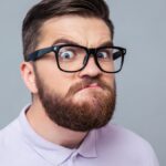 Portrait of a funny hipster man looking at camera over gray background.