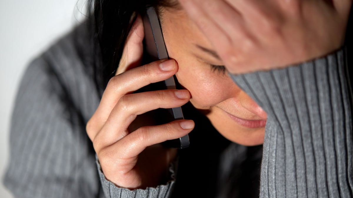 people, helpline and domestic violence concept - close up of unhappy woman crying and calling on smartphone.