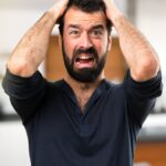 Frustrated handsome man with beard inside house.