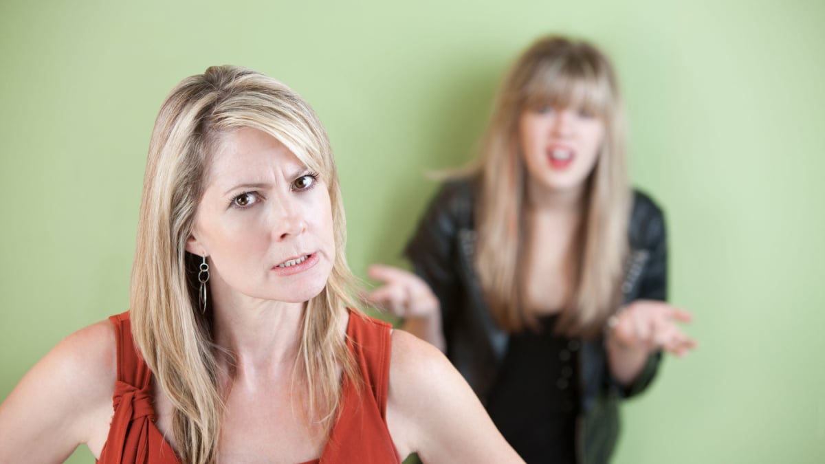 Angry mother with frustrated daughter in the background.