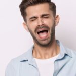 Head shot portrait of hysterical face expressions guy closed eyes screaming or whines isolated on grey white studio background, nagging man feeling desperate, singer singing song expressively concept.