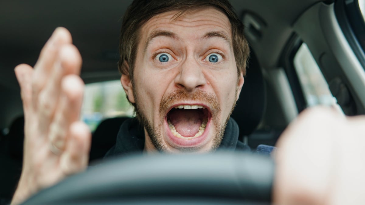 Angry man driving a car. Male driver gesturing and shouting behind the wheel of the car.