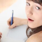 Young caucasian female student stands by school desk and cheat.