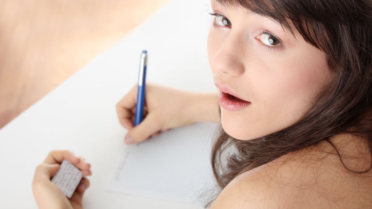 Young caucasian female student stands by school desk and cheat.