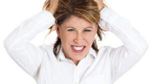 Closeup portrait of young stressed woman pulling her hair out about to have nervous breakdown, isolated on white background.