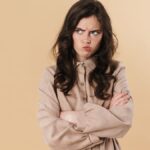 Image of resentful brunette woman posing and looking aside isolated over beige background.