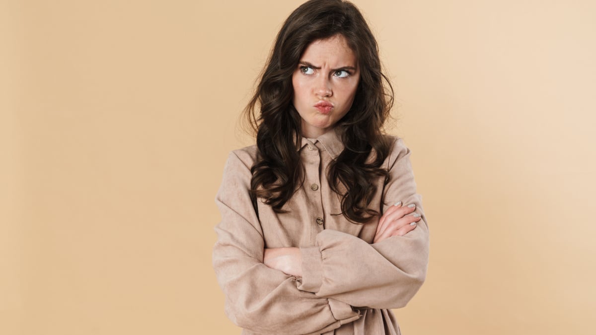 Image of resentful brunette woman posing and looking aside isolated over beige background.