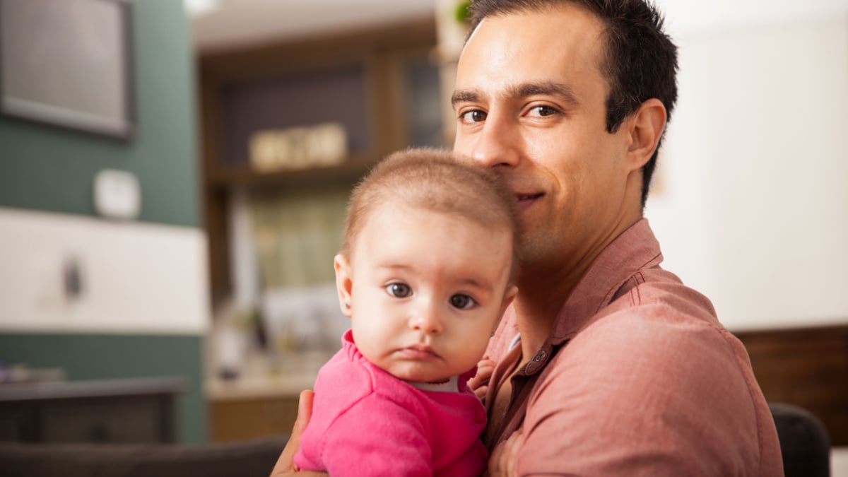 Attractive young single dad spending some time with his baby girl at home.