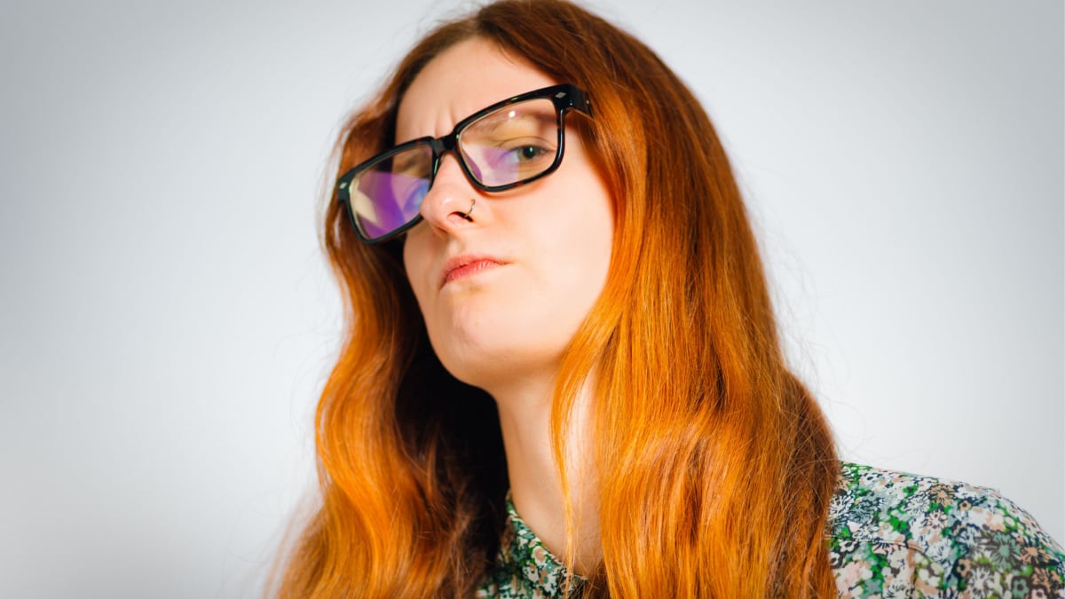 Redhead young woman looking condescendingly, isolated close-up.