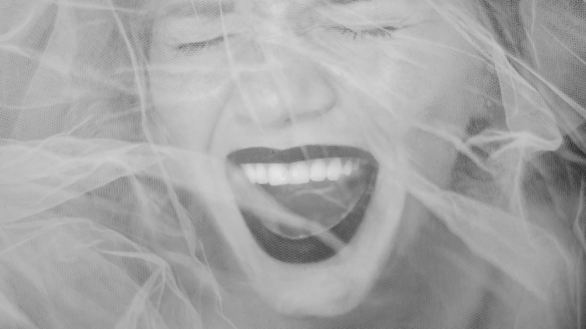 screaming face of a woman or a girl behind a veil. woman with black lips.