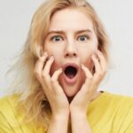 Woman in horror holds head with hands and screams of fear, anger and surprise isolated on white background. Something terrible and unexpected happened, expressive emotions.