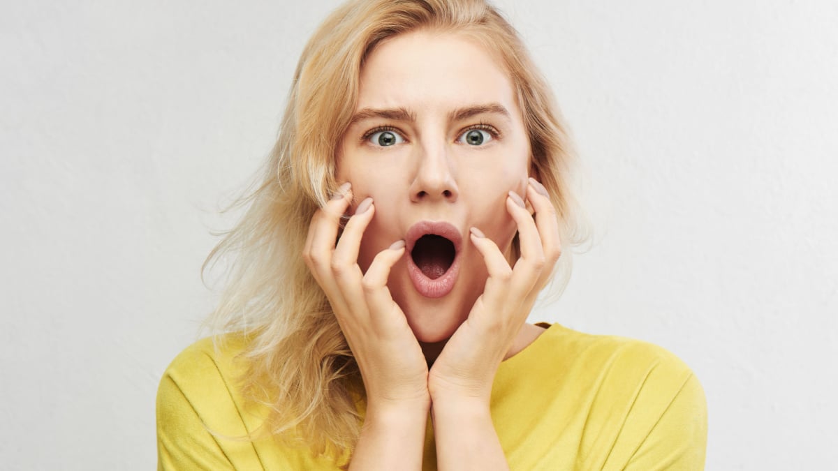 Woman in horror holds head with hands and screams of fear, anger and surprise isolated on white background. Something terrible and unexpected happened, expressive emotions.